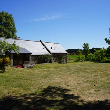 A sunlit view of the stone-built Mossyards cottages surrounded by open lawns, colourful flowerbeds, and peaceful countryside
