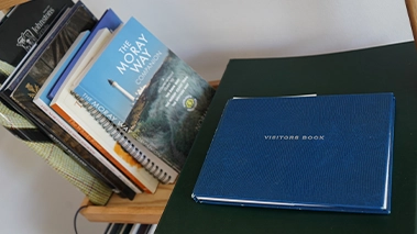 Close-up of books and a blue visitors book with The Moray Way Companion